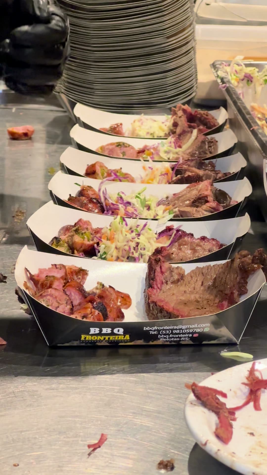 Fila de pratos de brisket com salada e picles, prontos pra servir